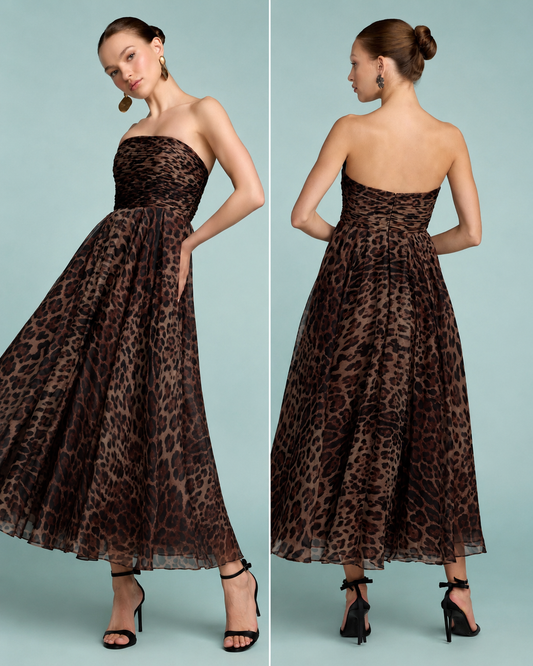 A woman modeling a strapless maxi dress with a brown and black leopard print pattern against a light blue background. Strapless brown and black leopard print maxi dress